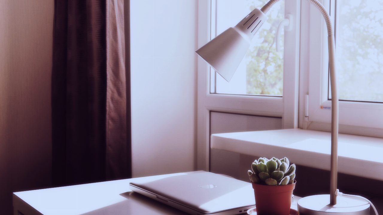 Closed laptop on a sunlit desk beside a window
