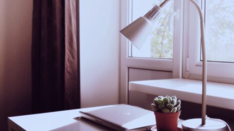 Closed laptop on a sunlit desk beside a window