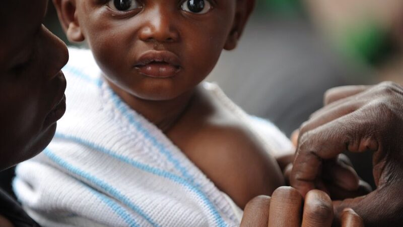 A young child being vaccinated by a health worker