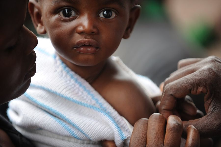 A young child being vaccinated by a health worker